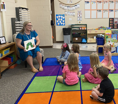 Mrs. Wieneke and students reading a book.