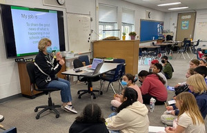 Woman presenting information to students in a classroom.